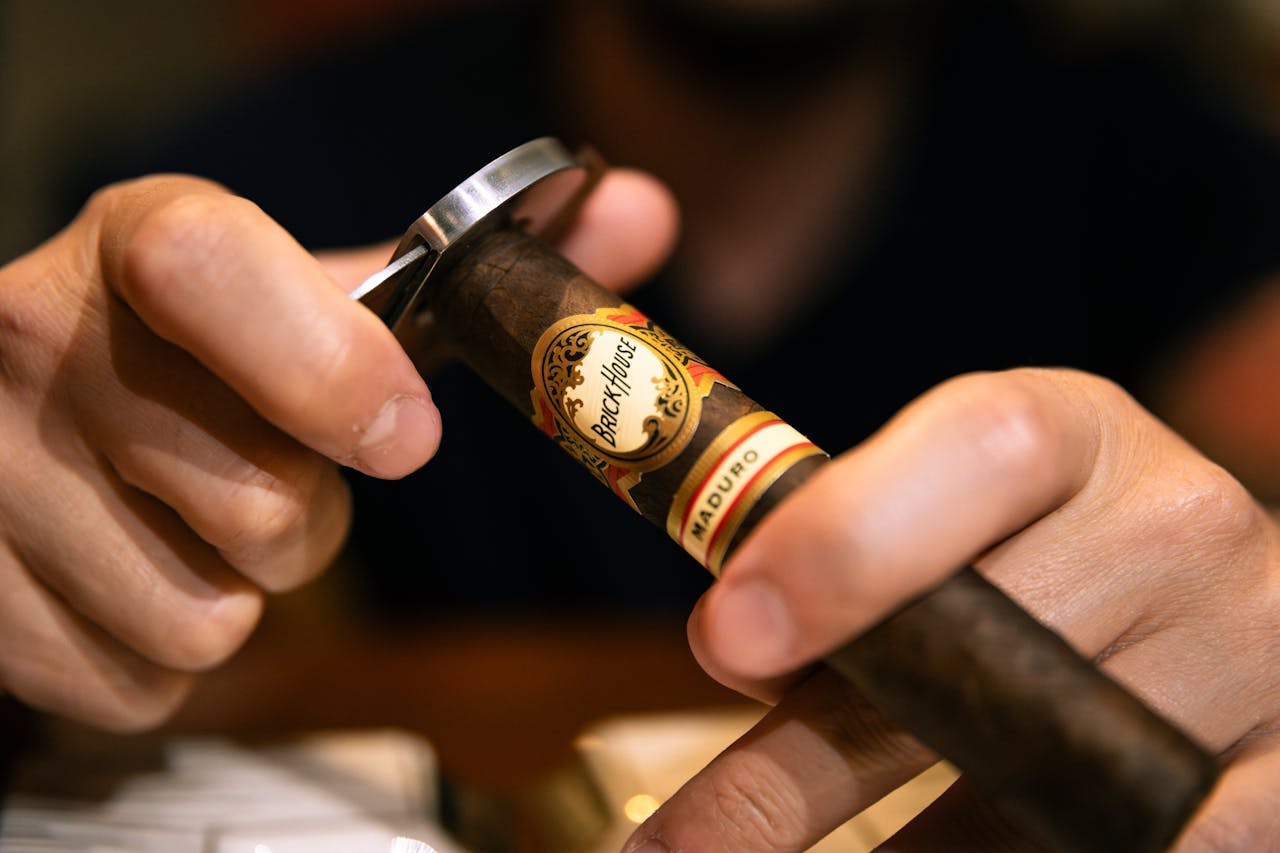 Close-up of a man using a cutter on a premium cigar for a precise smoking experience.