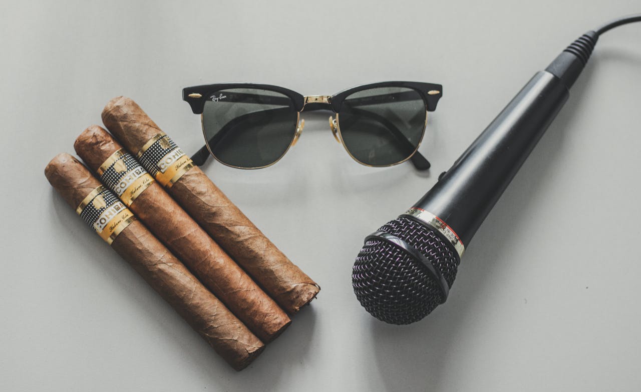 Top view of professional microphone near stylish black sunglasses and cigars on table